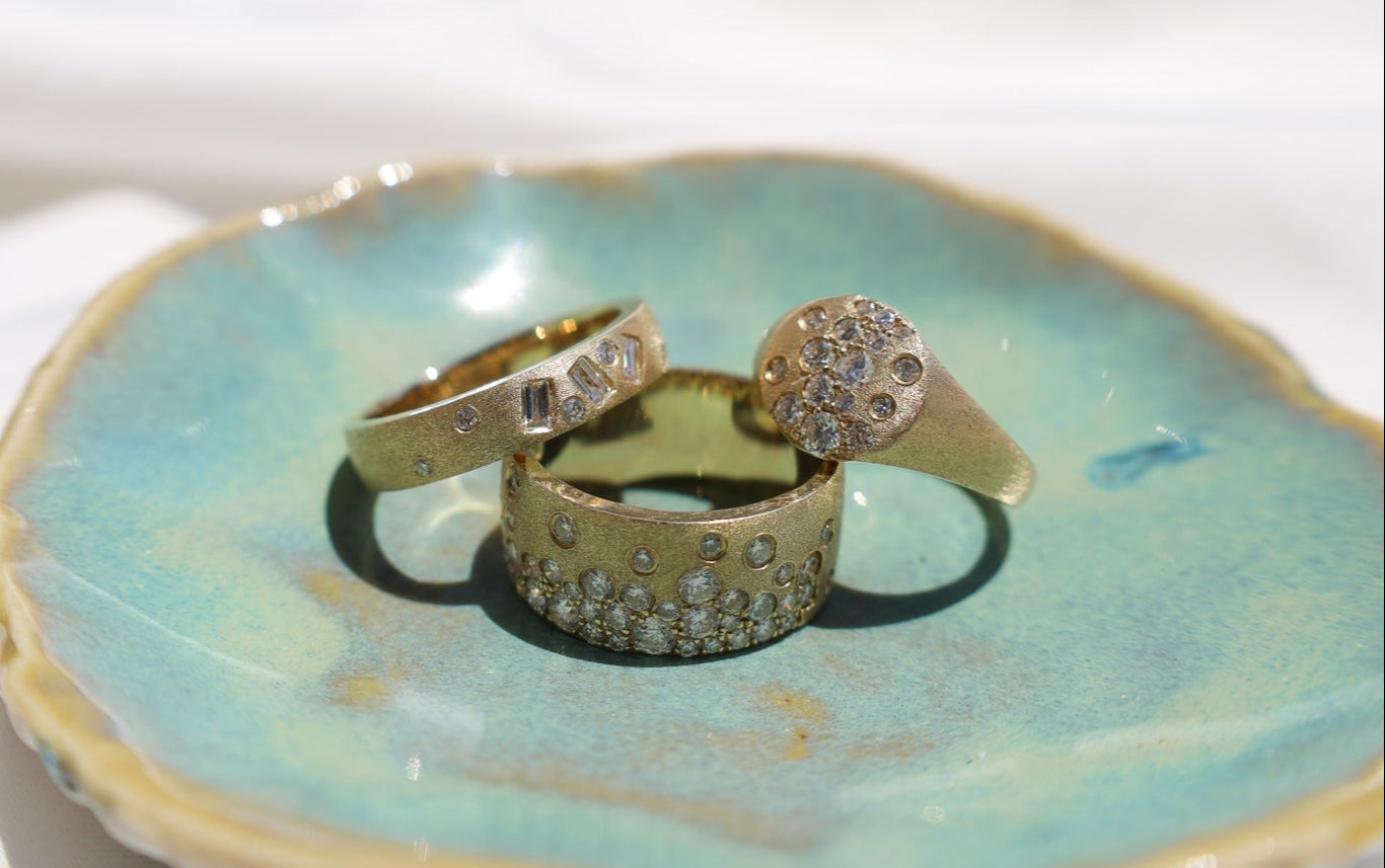 Gold rings with gemstones on a textured ceramic dish