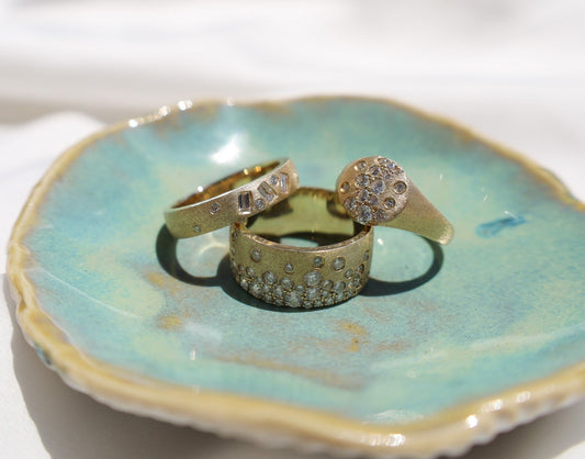 Gold rings with gemstones on a ceramic dish with a blue glaze.