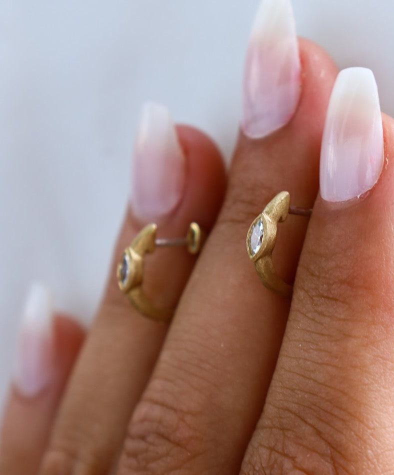 Gold hoop earrings on a hand with a blurred background