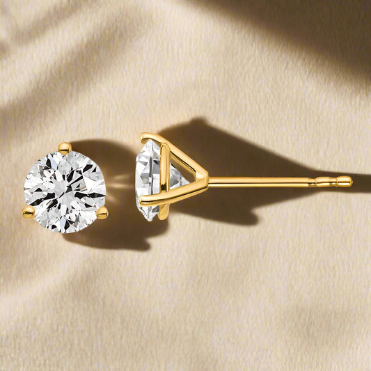 A pair of 14K gold three-prong lab grown diamond stud earrings.