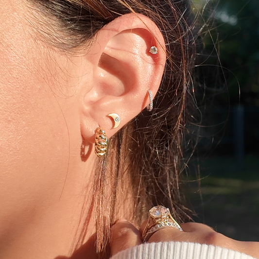 Close-up of a person's ear with earrings and a blurred outdoor background