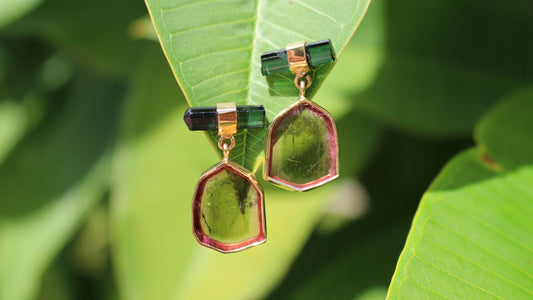 Green and gold tourmaline earrings hanging on green leaves