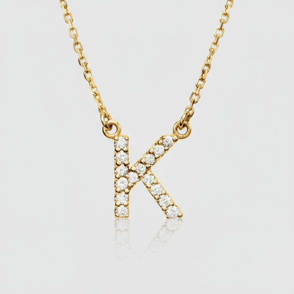 A gold diamond initial necklace with a personalized diamond pendant in the shape of the letter K, displayed against a neutral background.