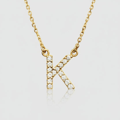 A gold diamond initial necklace with a personalized diamond pendant in the shape of the letter K, displayed against a neutral background.