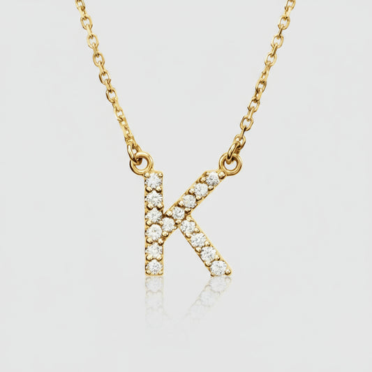 A gold diamond initial necklace with a personalized diamond pendant in the shape of the letter K, displayed against a neutral background.