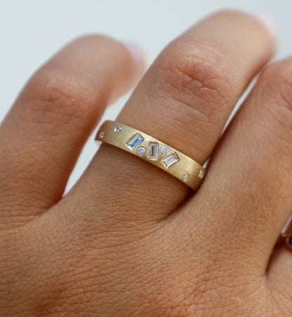 Gold ring with gemstones on a finger against a white background