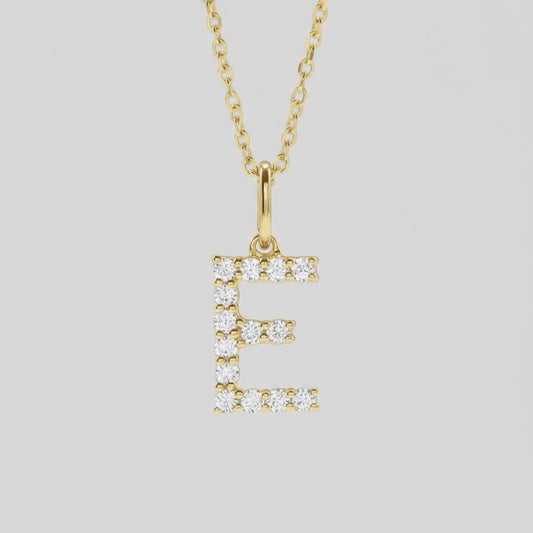 A gold lab grown diamond initial necklace with a personalized touch, displayed on a white marble surface.
