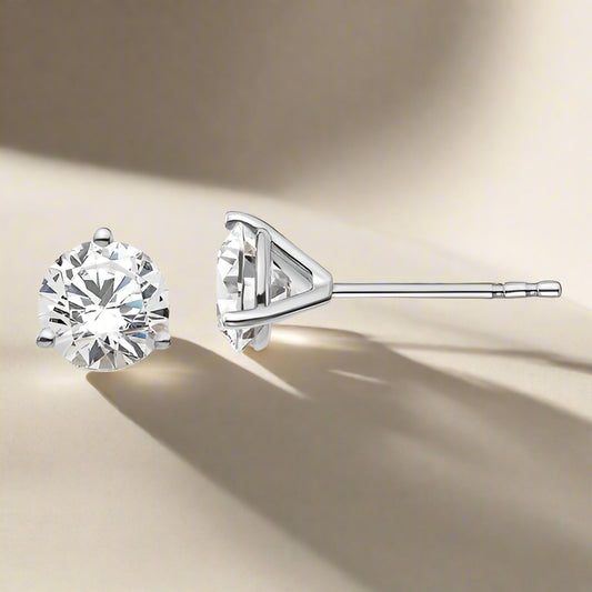 A pair of lab grown diamond stud earrings set in a solid 14K gold three prong setting, displayed against a neutral background.