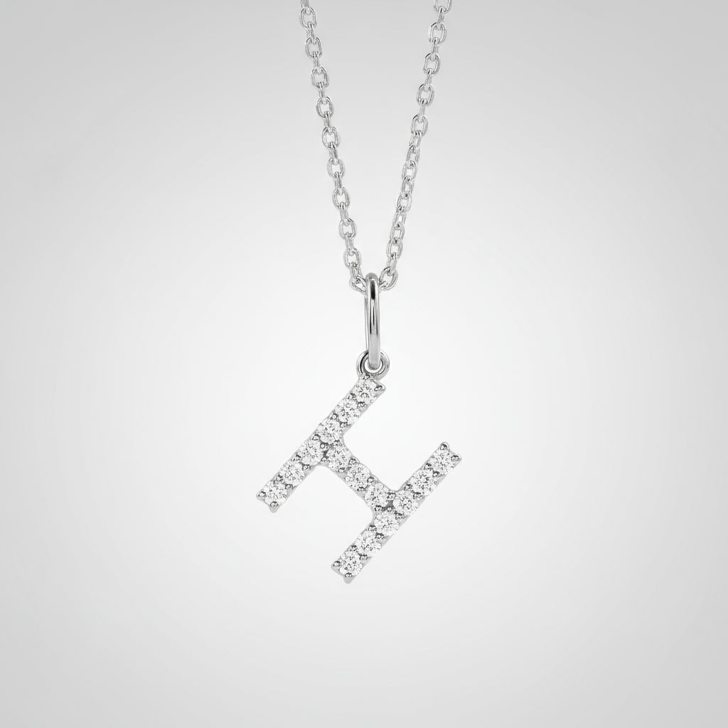 Silver necklace with a diamond-studded 'H' pendant on a light gray background