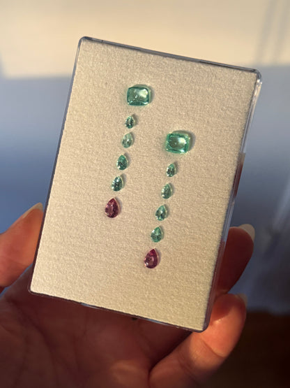 Collection of Paraíba tourmaline on a display card held by a hand.