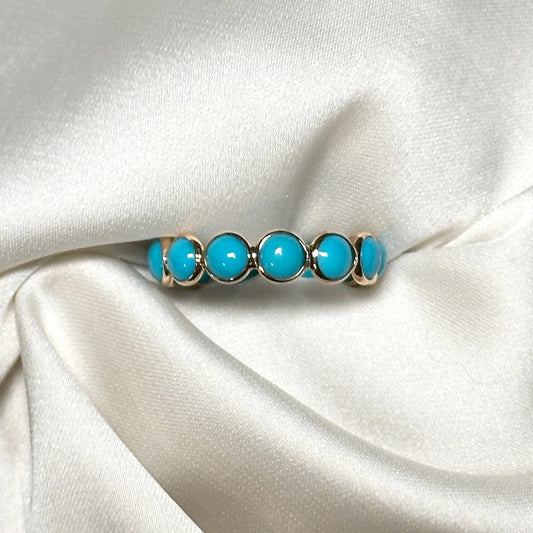 A ring set with a row of turquoise cabochons bezel set in 14K yellow gold