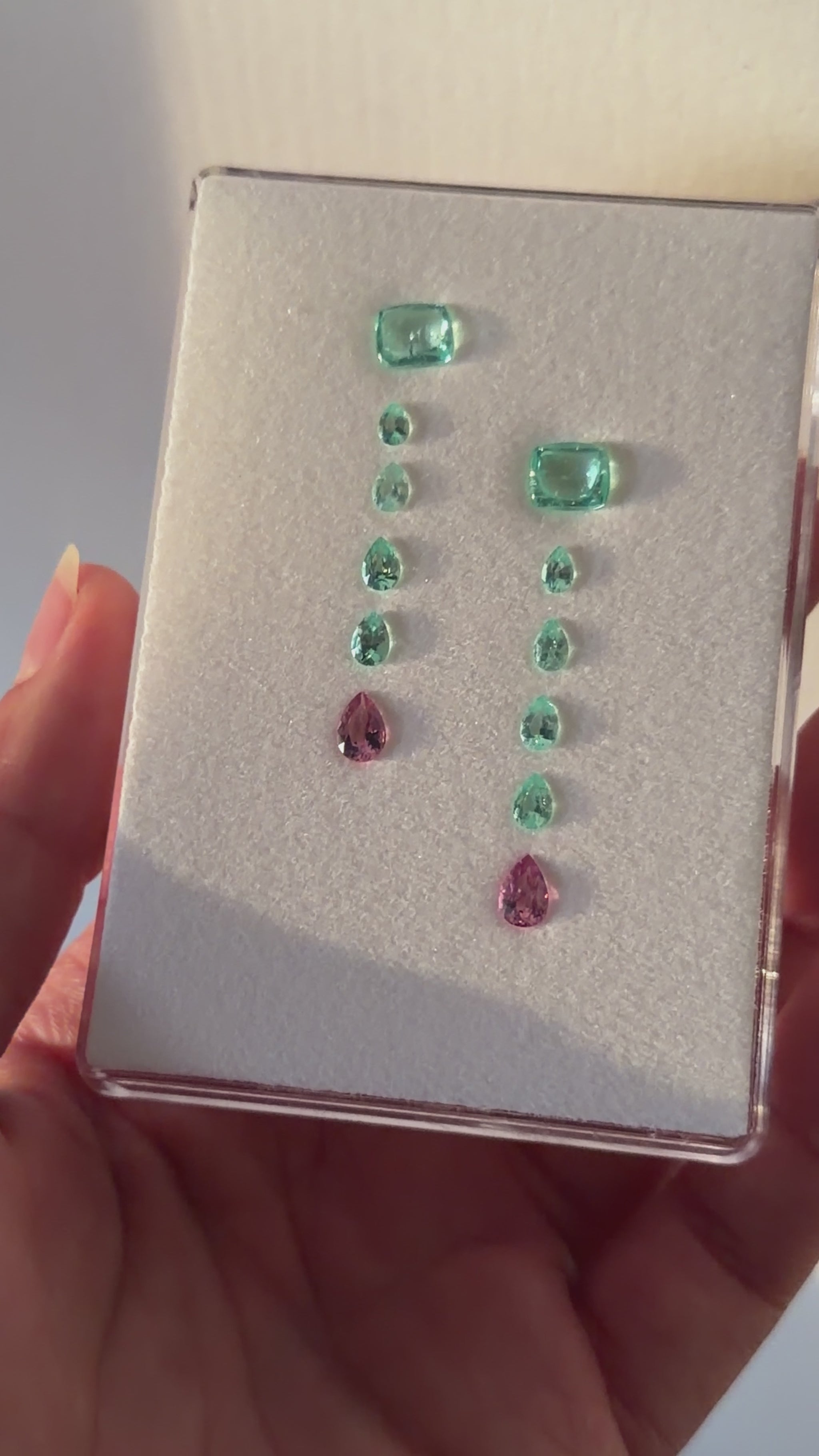 A layout of Paraíba Tourmaline gemstones in a pattern for a custom earring design