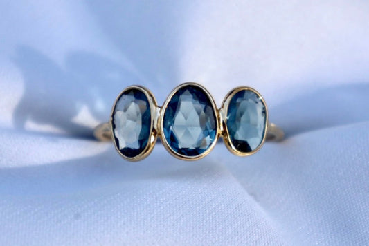A ring with three London Blue Topaz drops set in a gold band, displayed on a white background.