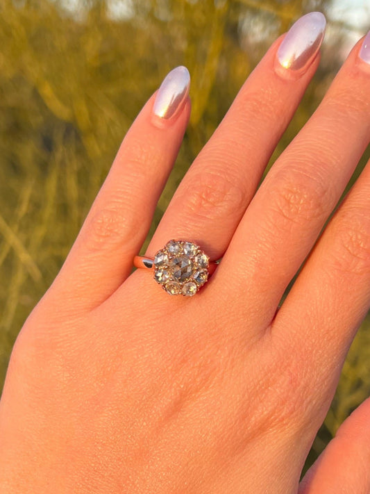 A hand displaying a antique rose cut diamond ring with a foil back set in a rose gold band, the ring is size 6.5 and appears ornate with a floral design like Lana Del Rey Engagement Ring