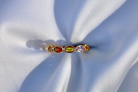 Ring set with oval shaped multi-colored sapphires bezel set in gold.
